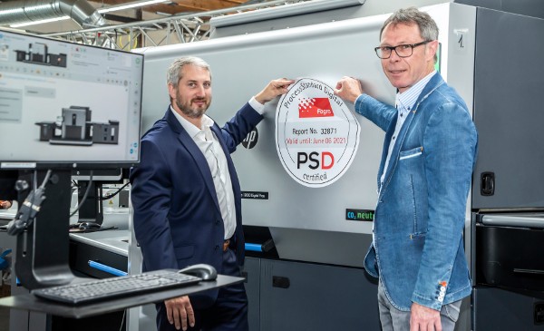 Ralf Schraud (izq.), director de impresión digital, y Thomas M. Schnitzler, gerente de CtP & Print QualityControl, colocan el sello que confirma que Onlineprinters cuenta con la certificación según ProcessStandard Digital (PSD). Copyright: Onlineprinters GmbH