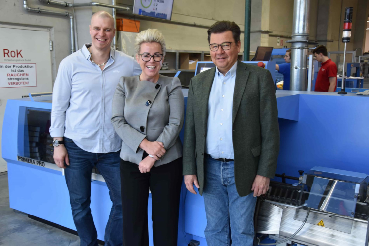 De izquierda a derecha: Stefan Riedl (Jefe de Encuadernaci&oacute;n), Daniela Klampfer (Directora General) y Roland Henn (Director Regional de M&uuml;ller Martini para Europa del Este) frente a la grapadora Primera PRO en la Imprenta Universitaria Klampfer GmbH.